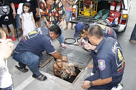 Rescuers pull Auy Ai from a storm drain after the little blind pooch somehow managed to get stuck inside.